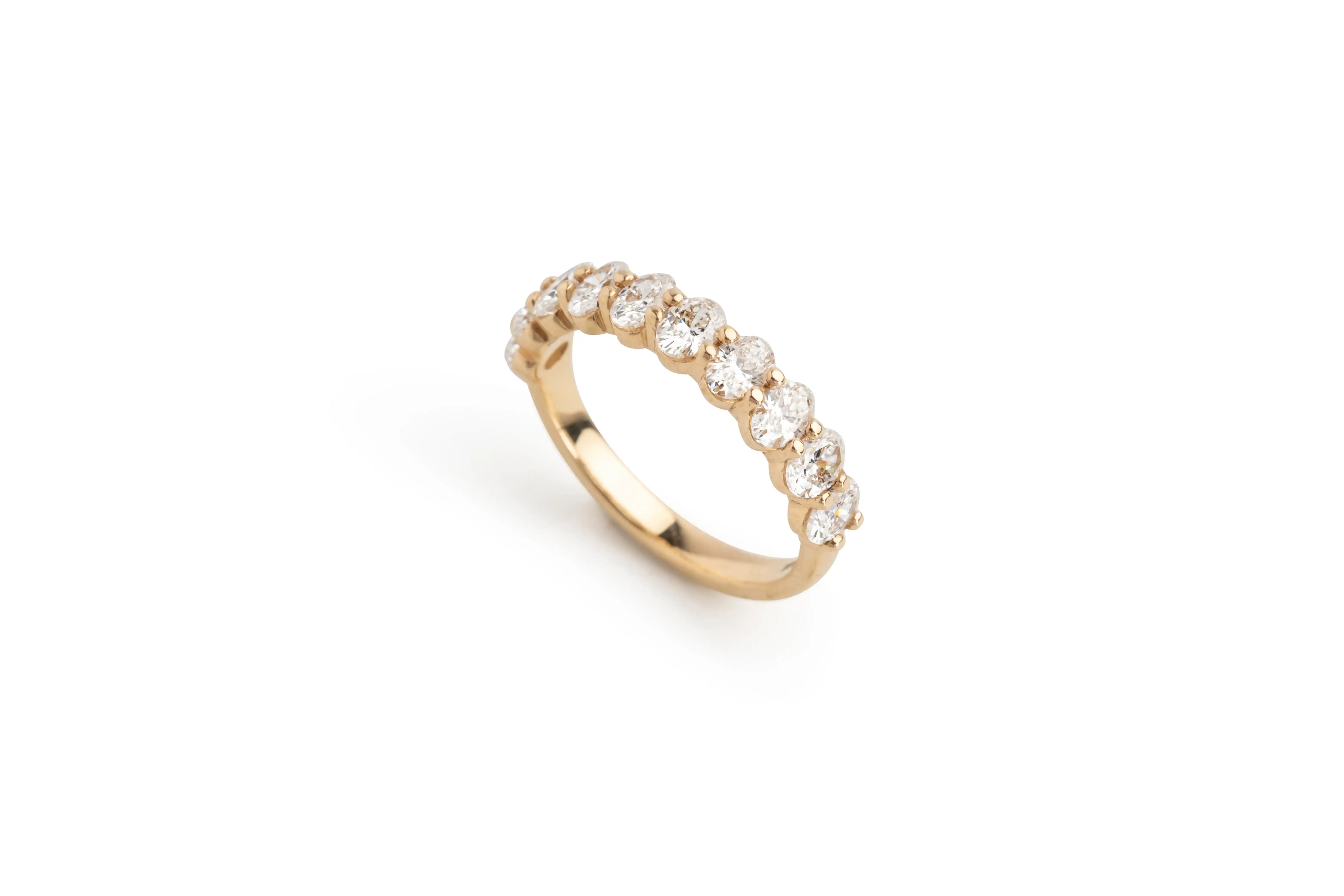 Gold eternity ring with round clear diamonds on white background