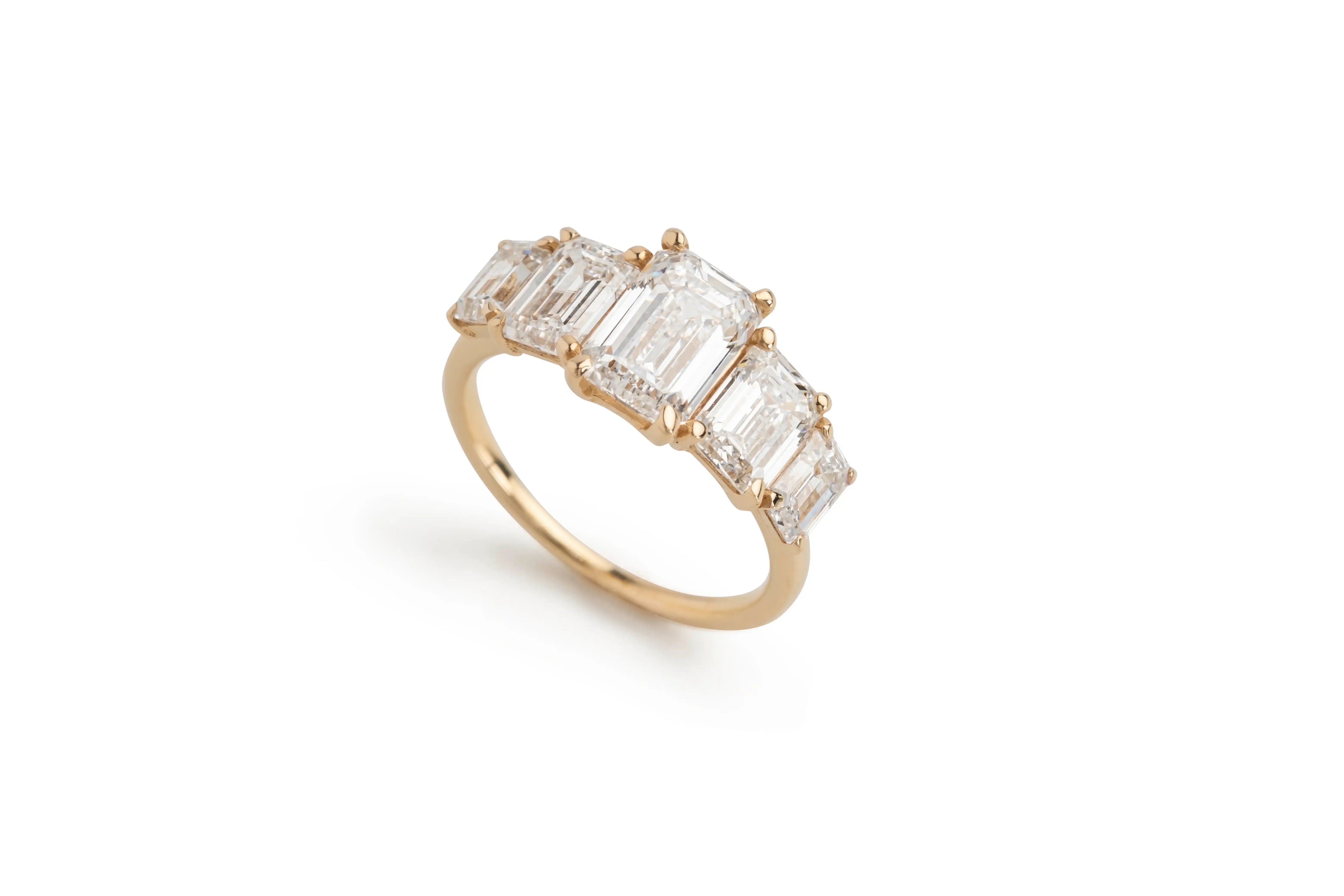 Gold ring featuring five rectangular emerald-cut diamonds on white background
